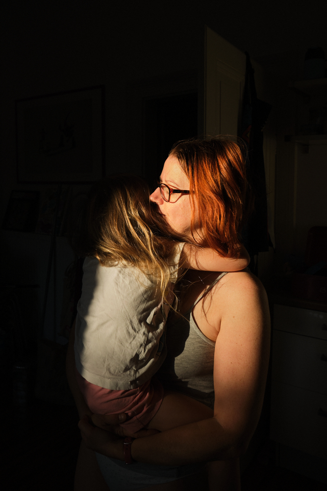 Authentische Familienfotografie in Worms: Die Fotografin umarmt ihr Kind im Morgenlicht