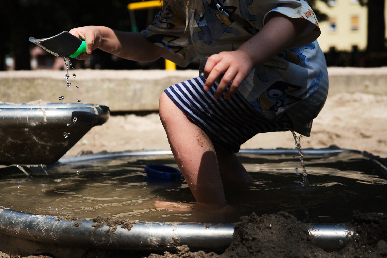Authentische Kinderfotografie in Worms: Kind spielt in der Matsche am Wasserspielplatz