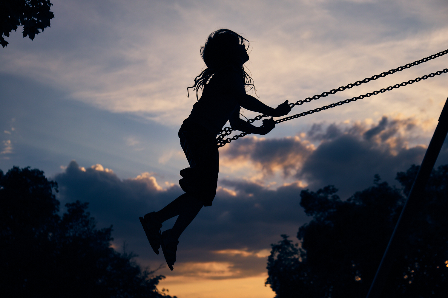 Kreative Familienfotografie in Worms: Die Silhouette eines Kindes auf einer Schaukel beim Sonnenuntergang